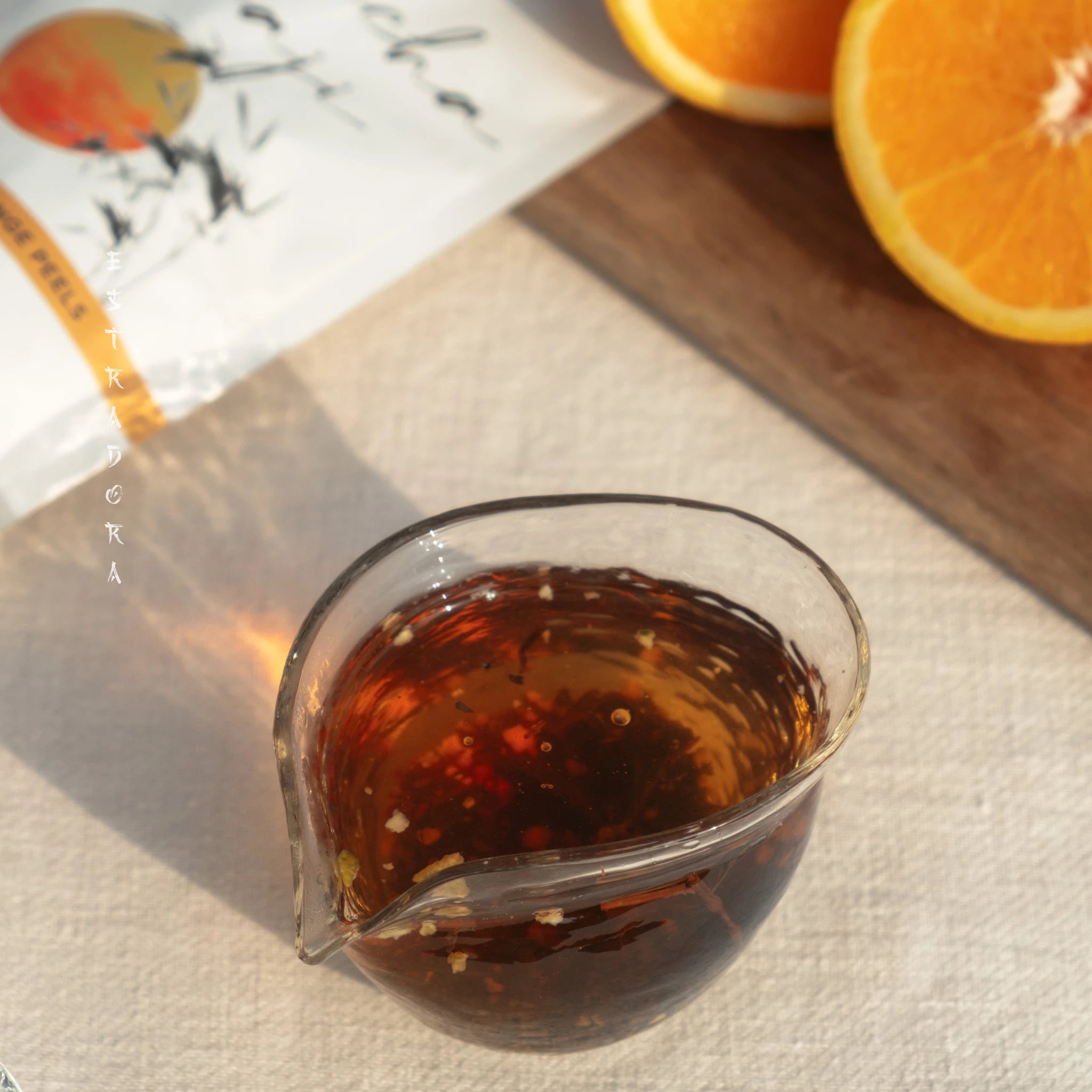 Brewed Wakoucha Keraji Japanese black tea with orange peels – rich amber color, fresh orange slices in background