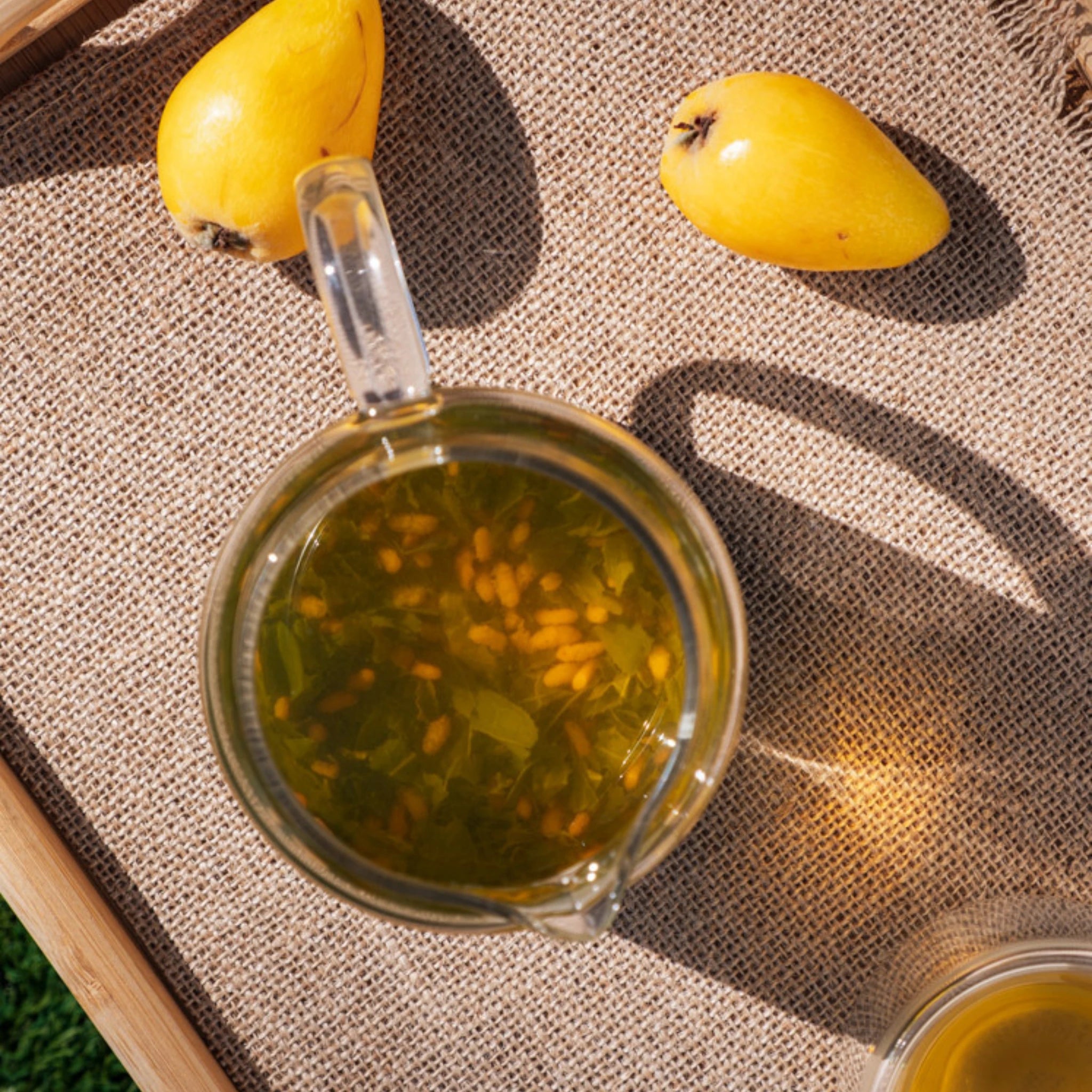 Brewed Japanese Genmaicha tea in glass teapot, outdoor natural light - Estradora