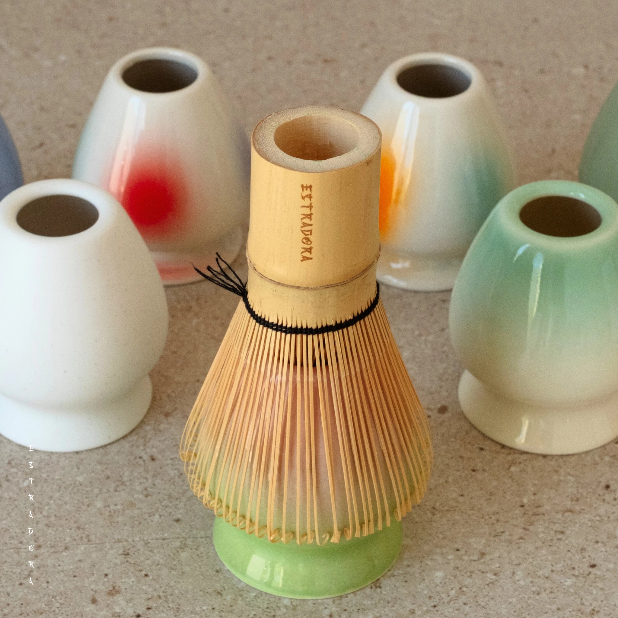 Matcha whisk placed in green ceramic whisk holder 
