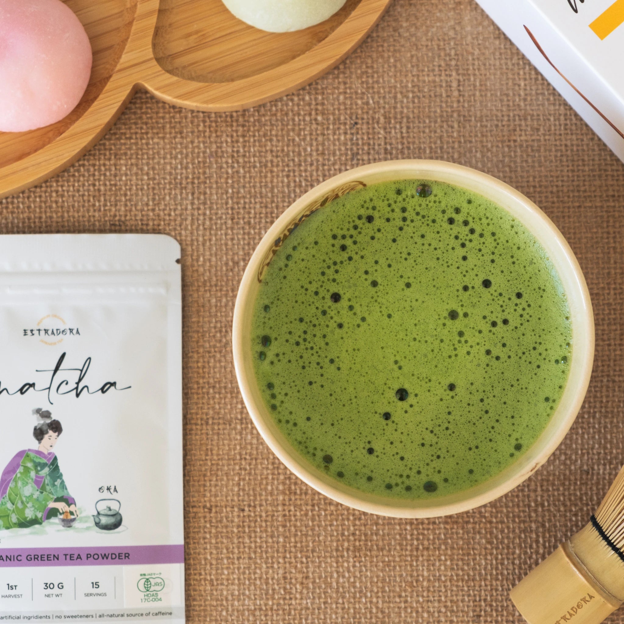 Japanese Matcha OKA tea prepared in ceramic bowl, with traditional mochi sweets and tea packaging 