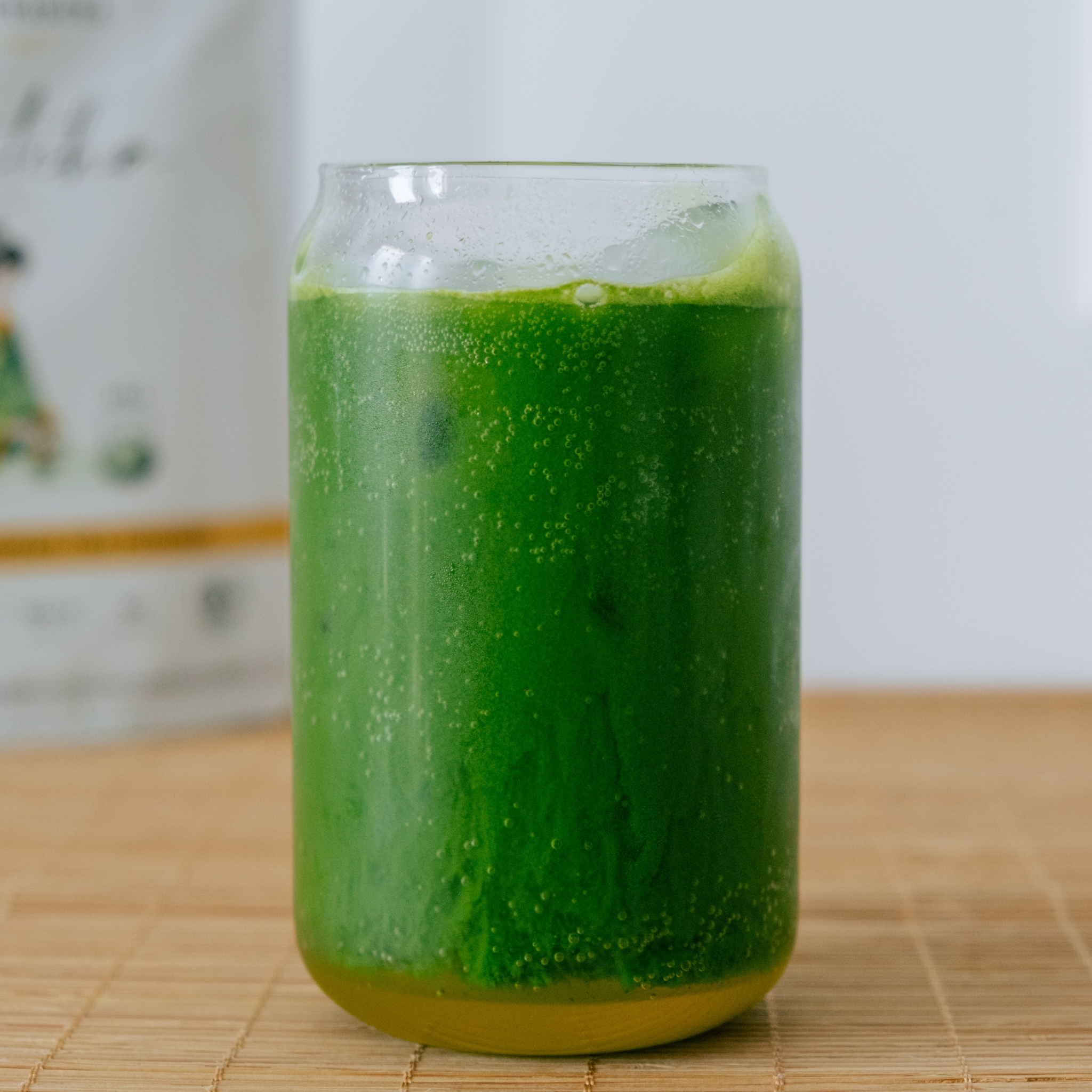 Iced UNA matcha in a glass, condensation on the surface, set on a bamboo mat.